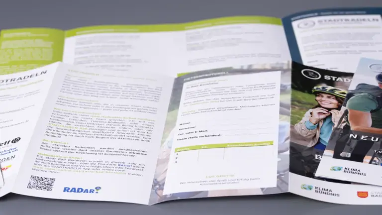 Aufgeklappte Wickelfalz-Flyer mit Innenseiten, Anmeldeformular und QR-Code