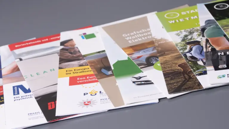 Zahlreiche Flyer verschiedener Auftraggeber aufgefächert auf einem Tisch