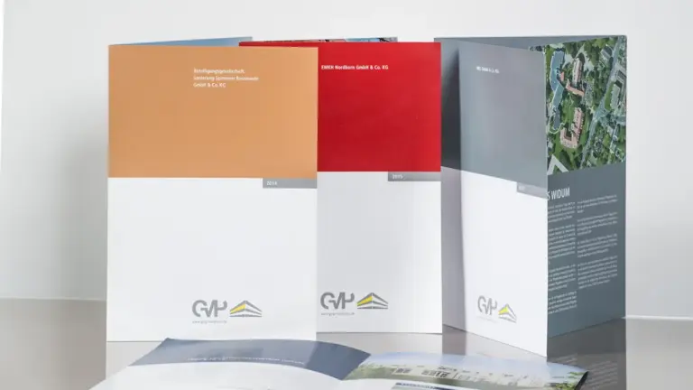 Drei Präsentationsmappen in verschiedenen Farben, eine davon aufgeschlagen