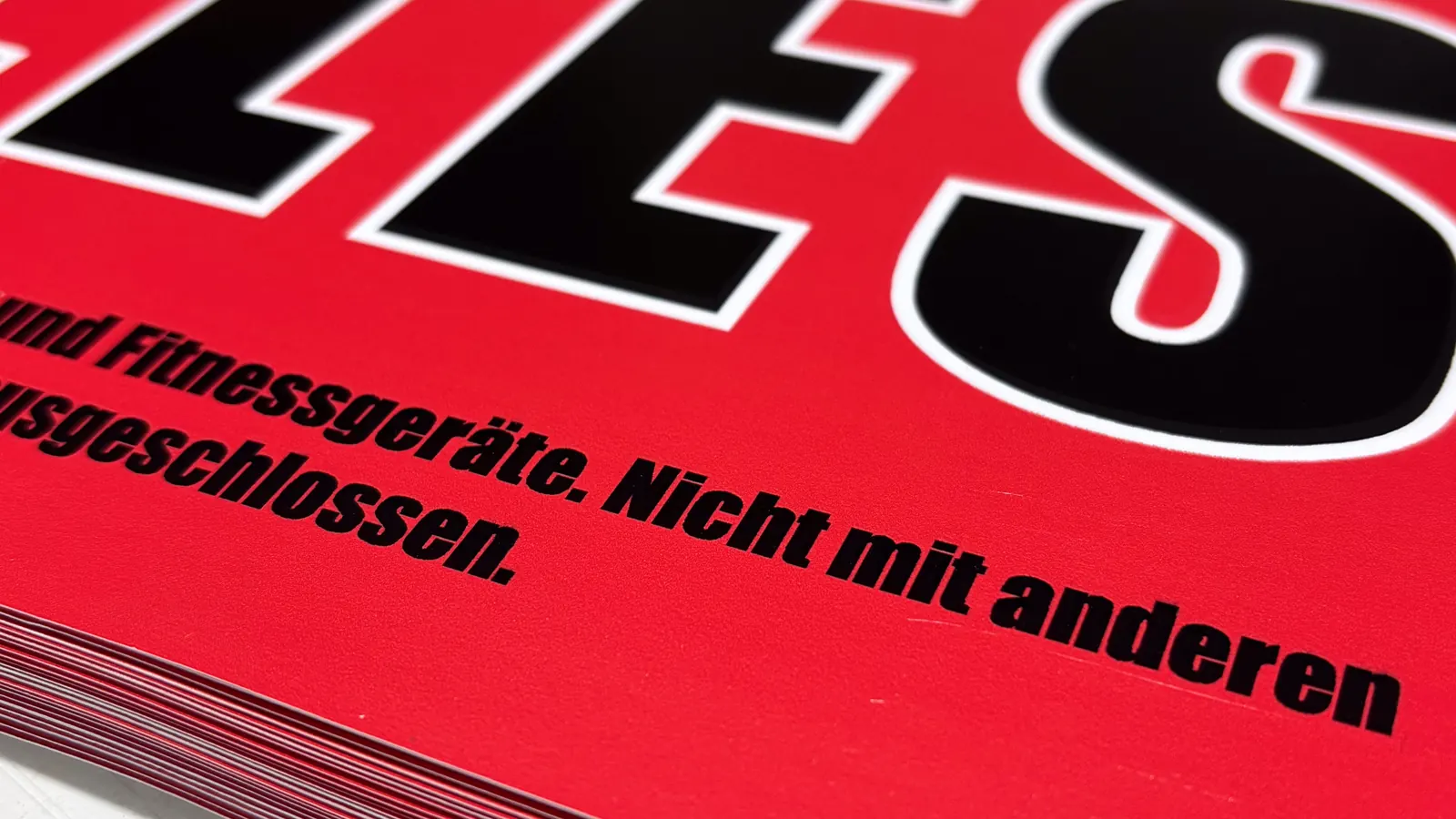 Stapel frisch gedruckter roter Plakate mit großer schwarzer Schrift, Nahaufnahme der Kante